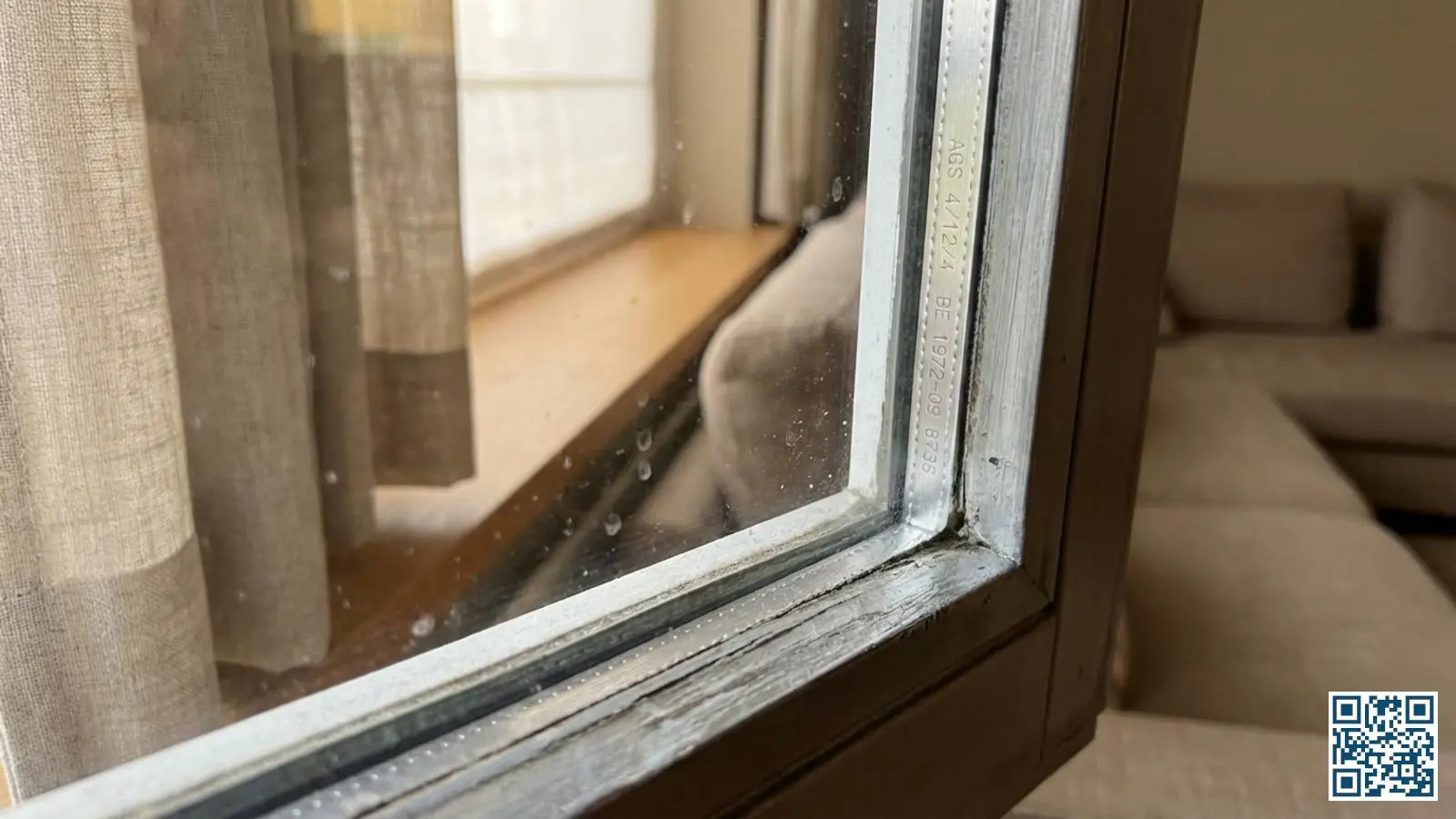 Close-up van de hoek van een isolatieruit met zichtbare meldcode gegraveerd in de spacer tussen de glasplaten